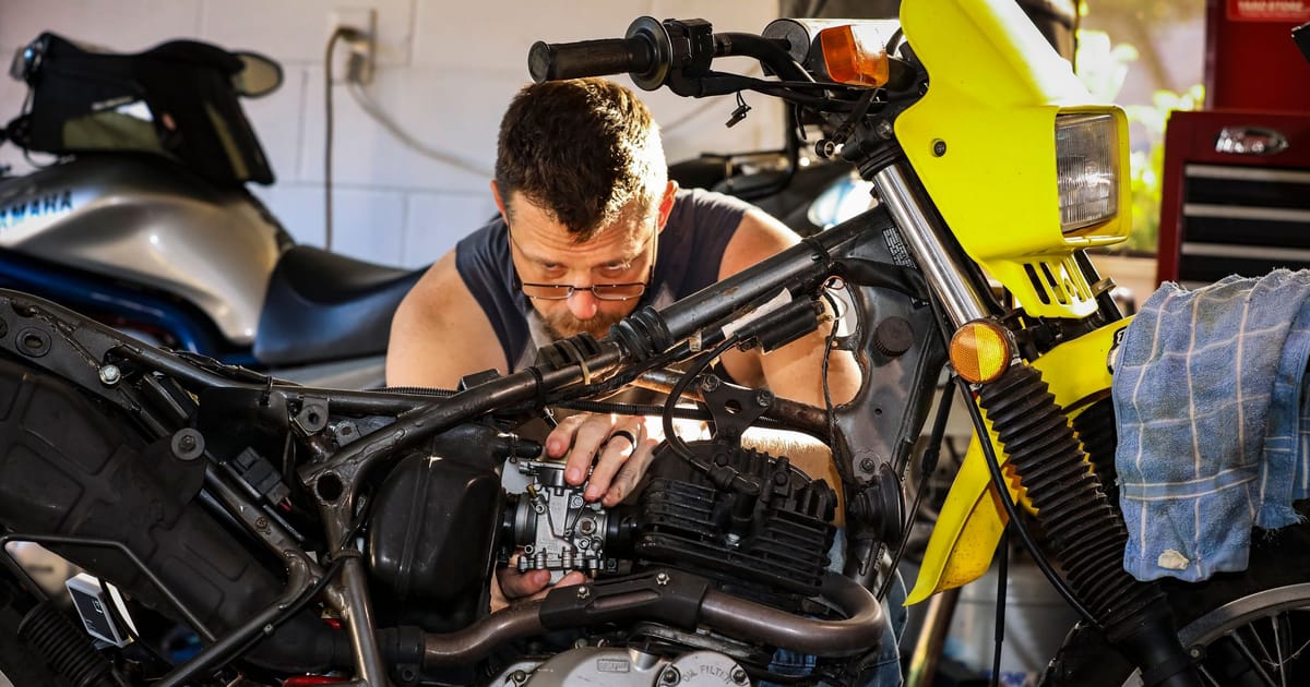 A mechanic working on a two-wheeler in a workshop.