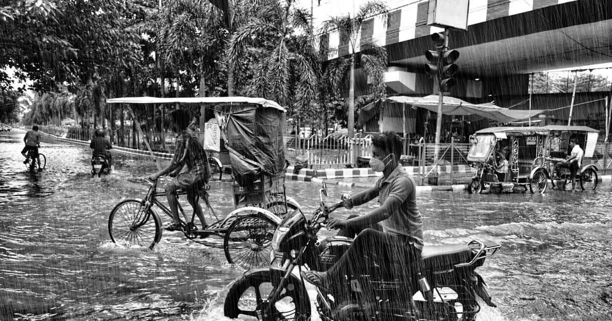 A rider on a flooded city street during monsoon rain.