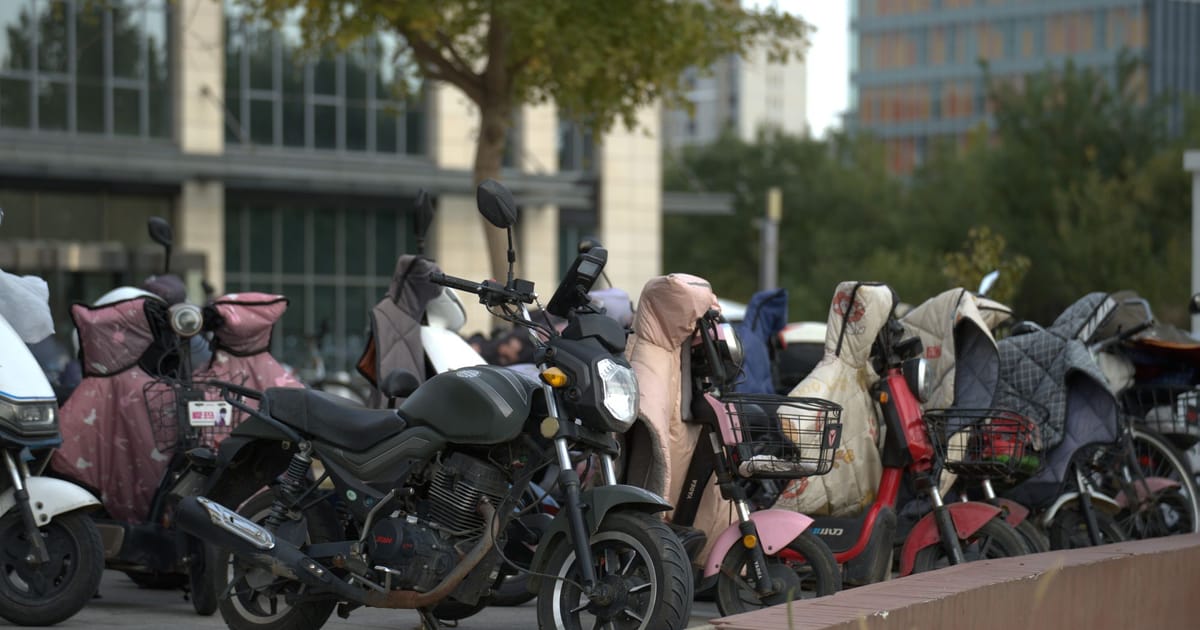 A motorcycle parked in front of a row of scooters.