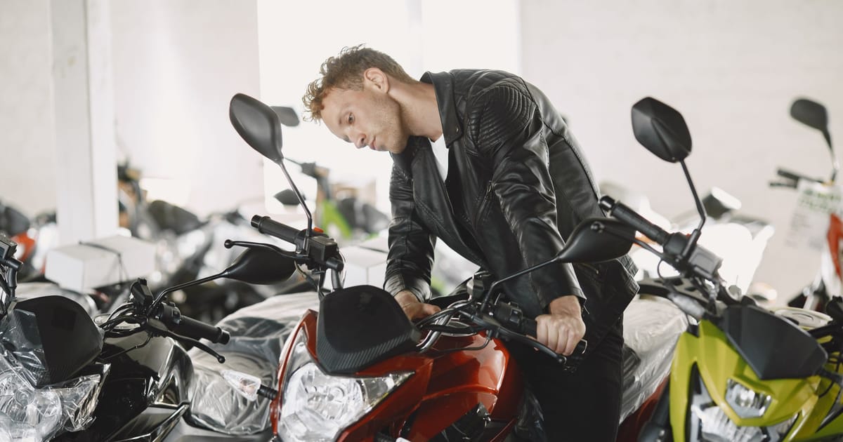 A rider looking over a row of motorcycles in a dealership.
